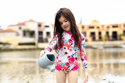 Blue plastic watering can toy held by a child outdoors