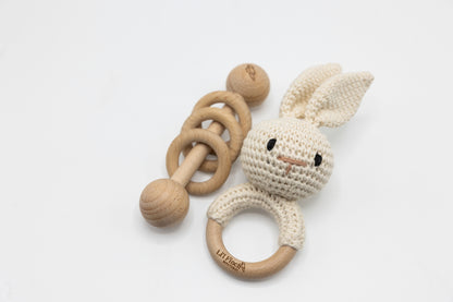 Cream crochet bunny baby rattle with wooden ring handle and teething circle.
