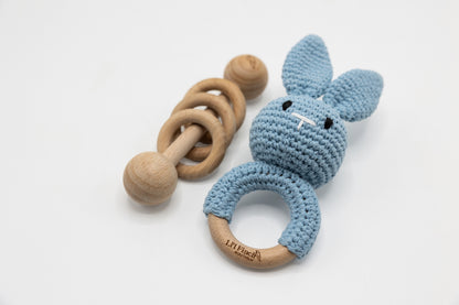 Light blue crochet bunny baby rattle with wooden ring handle and teething circle.