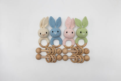 Assorted crochet bunny baby rattles with wooden ring teether in pastel colors.