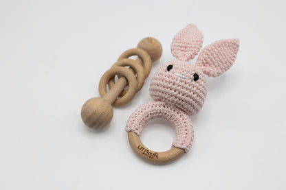 Pink crochet bunny baby rattle with wooden ring handle and teething circle.