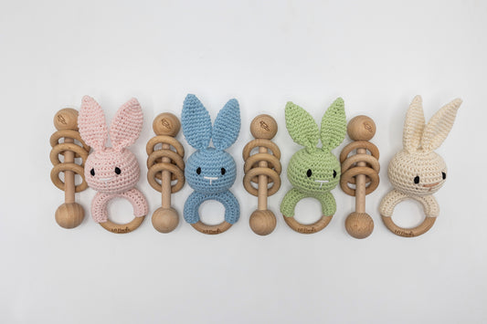 Mixed set of crochet bunny baby rattles with wooden ring teether in pastel tones.