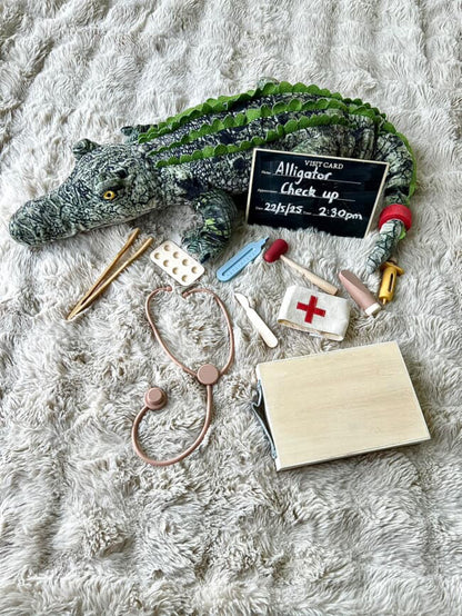 Toy doctor play accessories laid out on a plush blanket, including stethoscope and cards