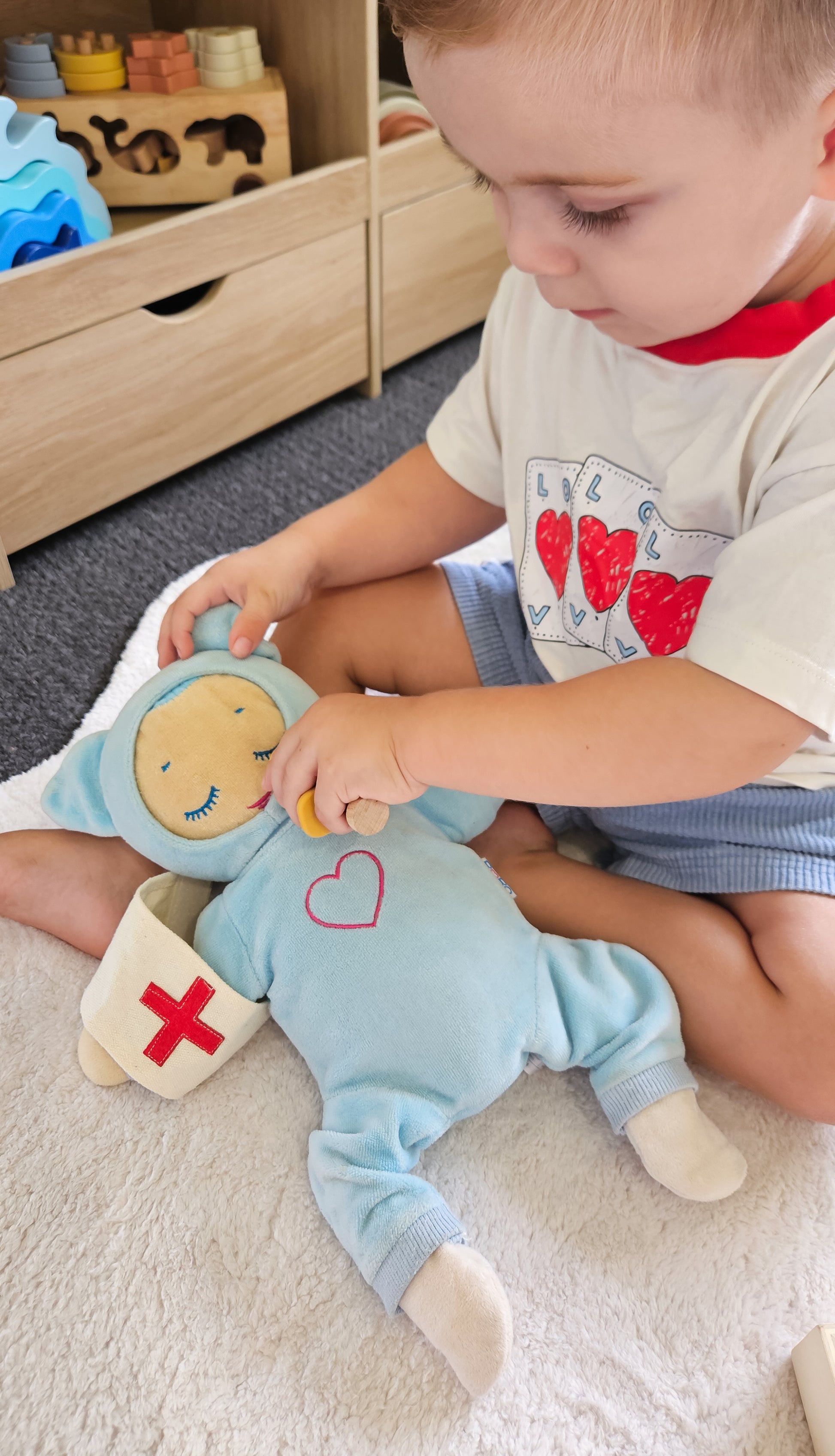 Child role playing doctors with a plush toy in a room with a silicone doctors set 