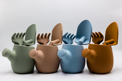 Set of pastel plastic watering cans with rake and spade attachments