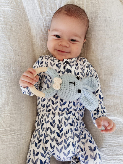 Blue crochet bunny baby rattle with wooden ring handle, held by a baby.