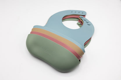 Dusty blue silicone bucket bib with rainbow accent band and snap details