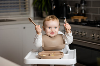 Latte beige silicone bucket bib on toddler in high chair
