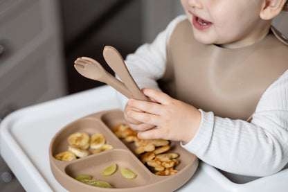 Latte beige silicone bucket bib on toddler during mealtime