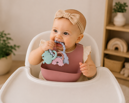 Baby holding a pastel teething ring with textured links and beads