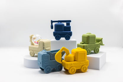 Stacked construction bath toy trucks in blue, yellow, green, and beige with different body shapes