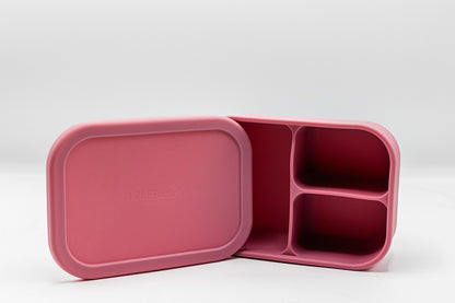 Pink bento box with two compartments and an open lid, showing the inner sections