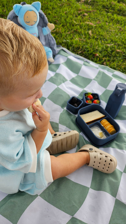 Blue bento box with divided compartments and a hinged lid, with food pieces inside