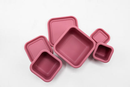 Pink silicone snack box set with three square trays and a small cup