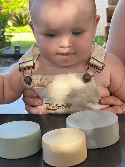 Three stacking cups on a table in pale gray, cream, and beige