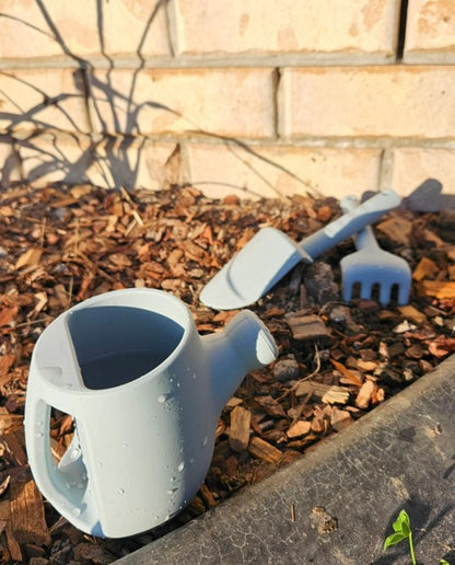 Kids watering can and garden tools toy set with light blue pieces by soil and brick