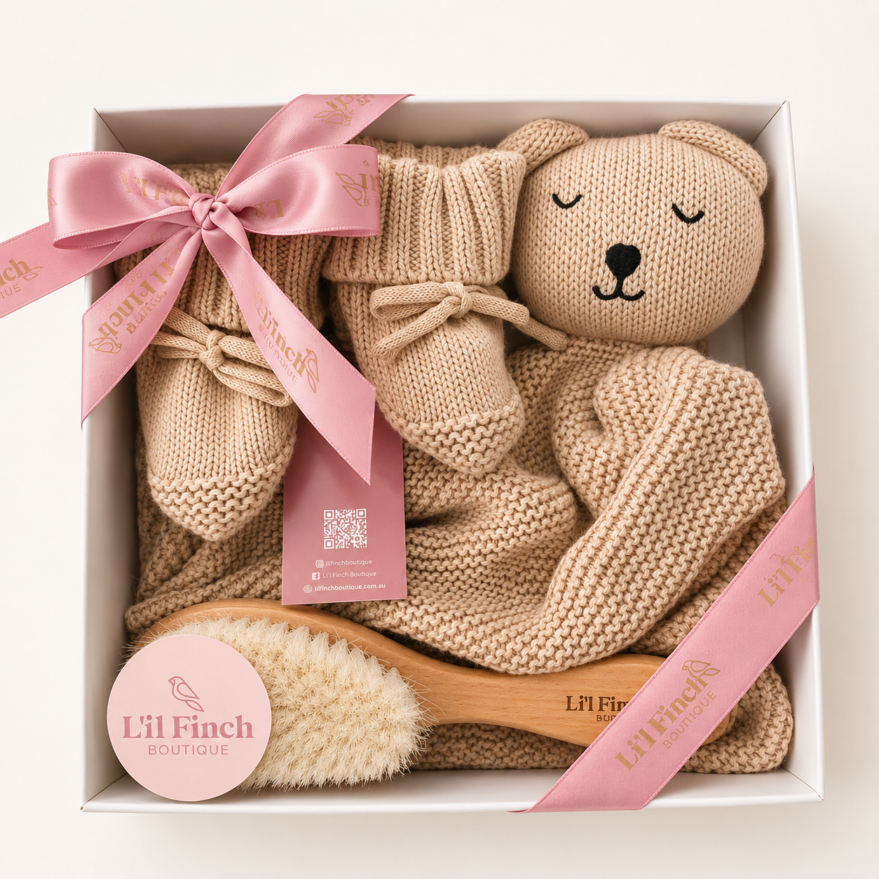 Baby gift set with knitted items and a brush in a box, branded 'Lil Finch Boutique'.