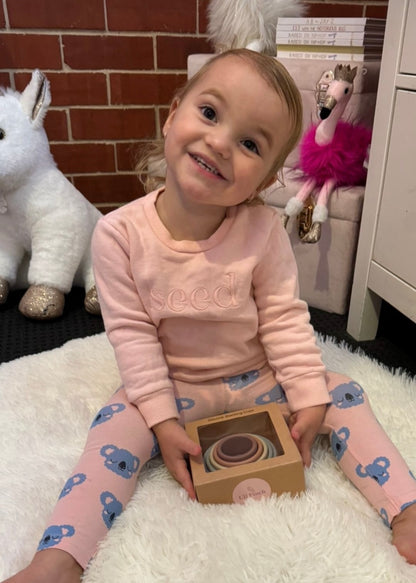Baby with a toy box and stacking cups set on a soft white surface